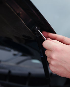 Screwdriver loosening spring clips on struts