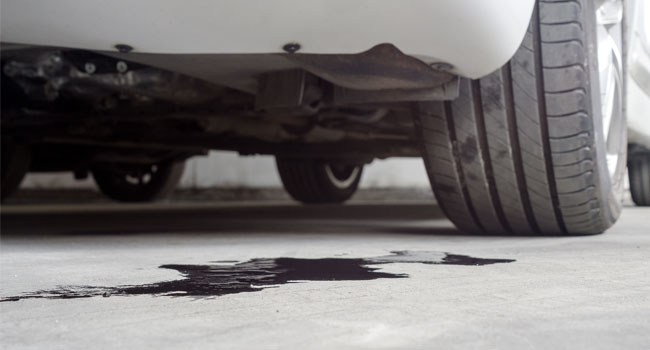 Puddle of motor oil under a white car