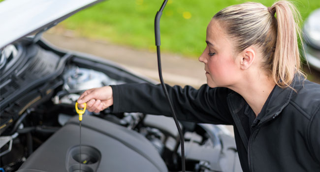 Woman checking engine oil with dipstick
