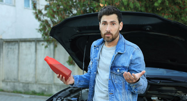 Man holding engine oil container and shrugging